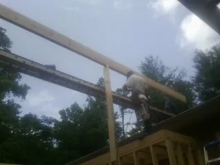 Carpenter setting a ridge beam over a new addition frame — Ice Dam Removal by Roofing Brothers in Manvel