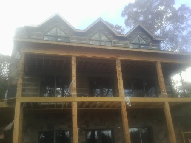 Dormers and porch framing on a large log home under construction — Roof Coating work by our crew in Manvel