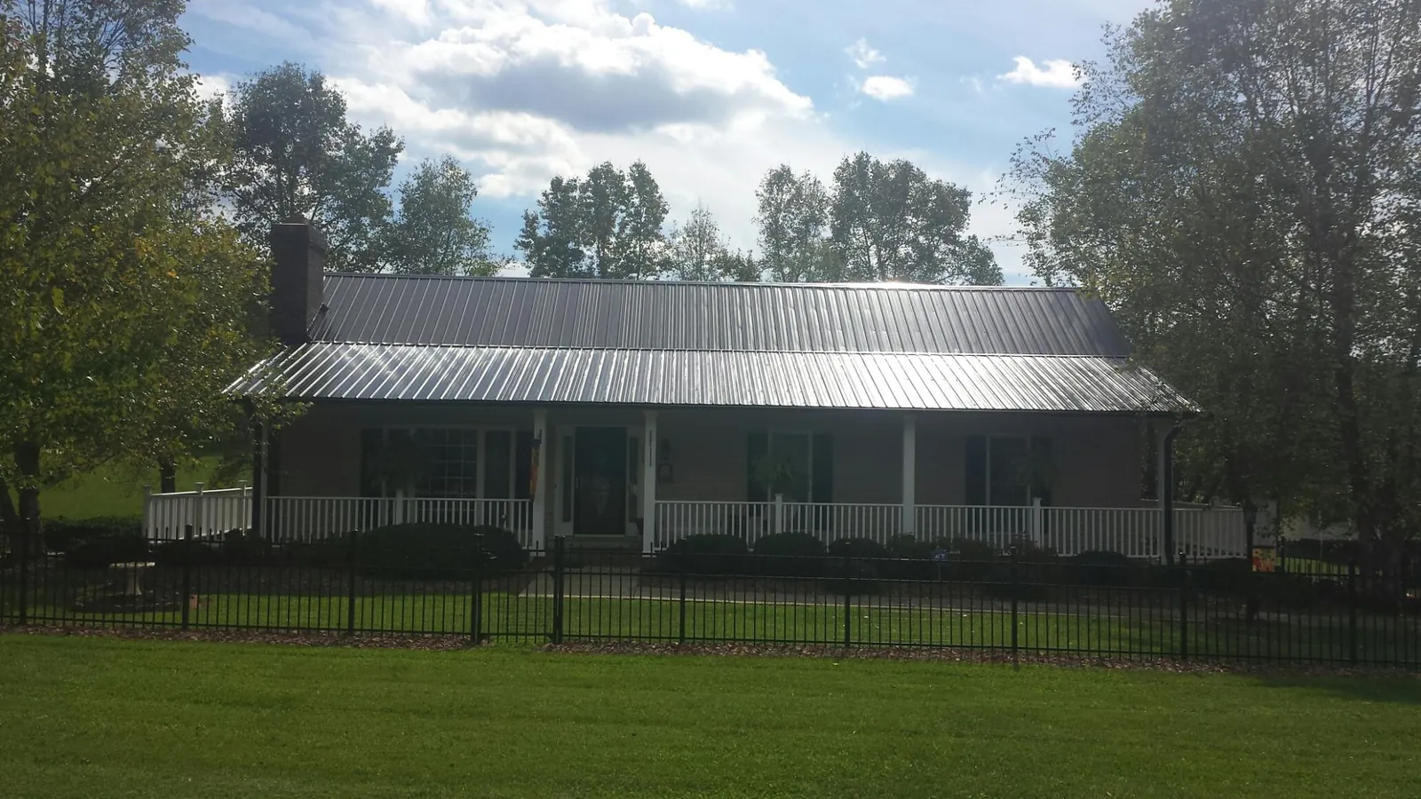 Gray metal roof on a brick ranch with a full width front porch — Gutter Guard Installation work by our crew in Manvel